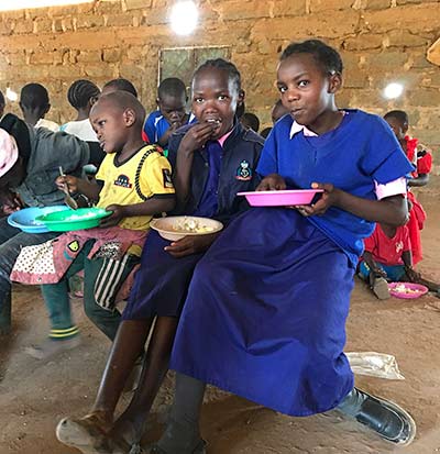 girls in a kcef school eating a free lunch provided by the school