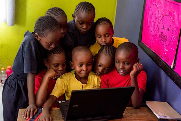 group of students huddled over laptop