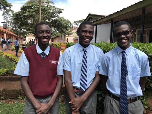 group of male students smiling at their high school in kenya