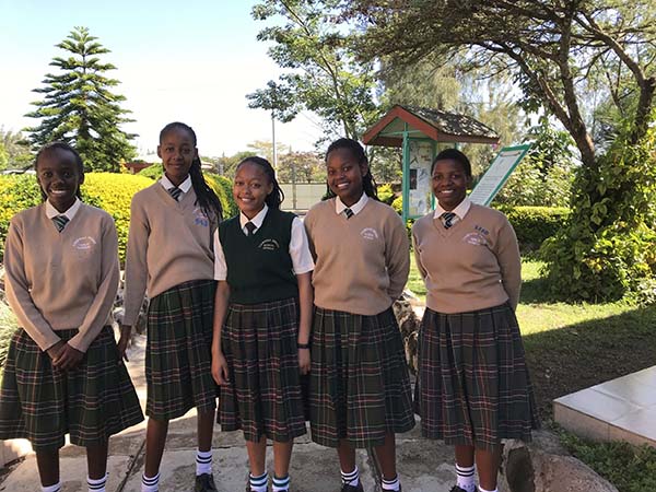 group of kenyan high school girls smiling in a school courtyard