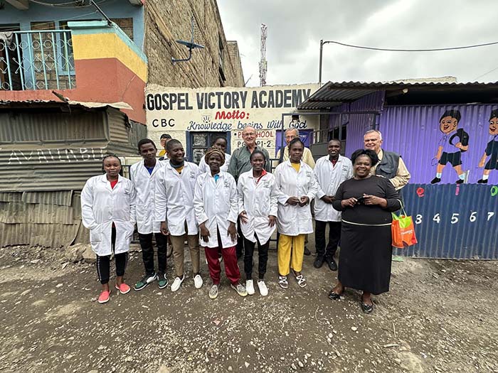 students of gospel victory academy in kenya standing with their teacher