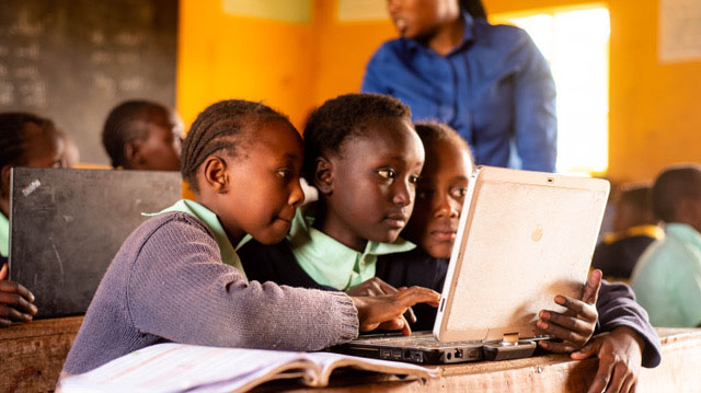 two young students working together on a laptop in a classroom
