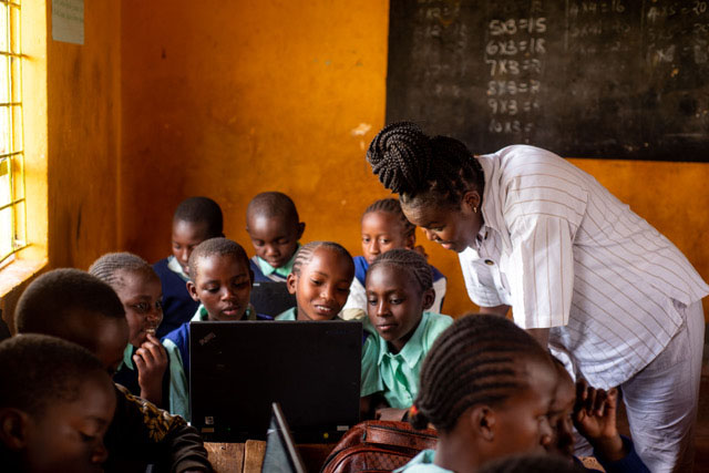 teacher at thika-penuel working with kids on their laptops