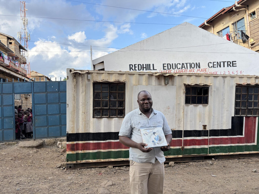 Andrew stands in front of the Red Hill school
